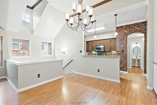 kitchen with light hardwood / wood-style floors, kitchen peninsula, hanging light fixtures, and ornamental molding