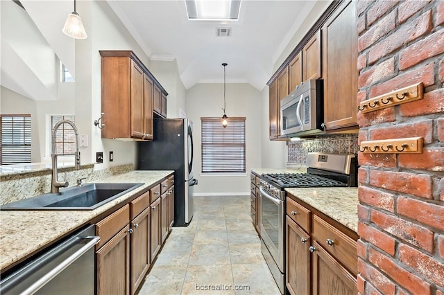 kitchen featuring light stone countertops, sink, stainless steel appliances, crown molding, and decorative light fixtures