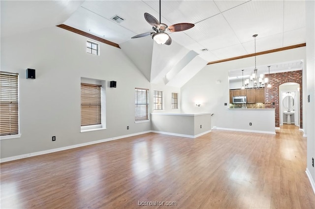 unfurnished living room with ceiling fan with notable chandelier, light hardwood / wood-style floors, and vaulted ceiling