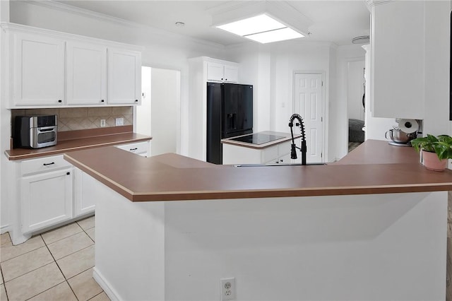 kitchen featuring light tile patterned floors, tasteful backsplash, white cabinetry, and black appliances