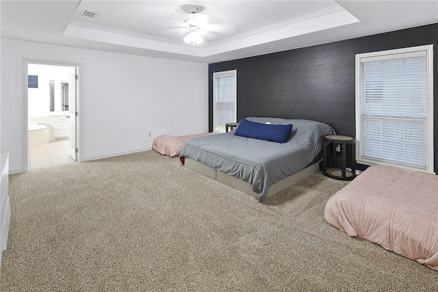 bedroom featuring a tray ceiling, crown molding, light colored carpet, and ensuite bathroom