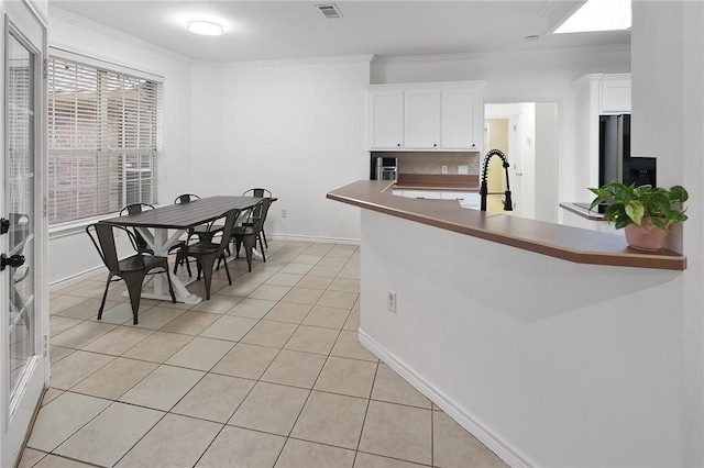 kitchen with white cabinetry, ornamental molding, decorative backsplash, and light tile patterned floors