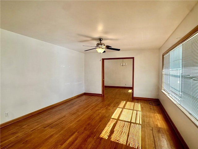 unfurnished room featuring hardwood / wood-style floors and ceiling fan with notable chandelier