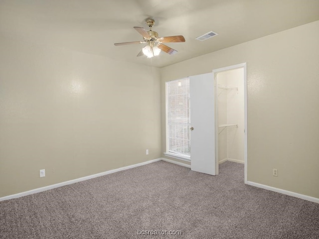 unfurnished bedroom with carpet, a closet, a spacious closet, and ceiling fan