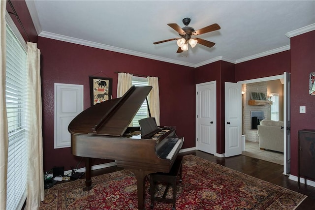 office featuring crown molding, a ceiling fan, wood finished floors, baseboards, and a brick fireplace