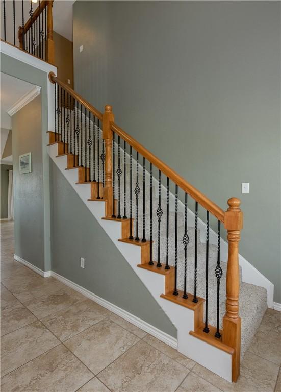 stairs featuring a towering ceiling, baseboards, and ornamental molding