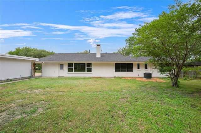 back of property featuring stucco siding, a chimney, central AC, and a yard