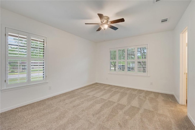 empty room featuring visible vents, ceiling fan, light colored carpet, and baseboards