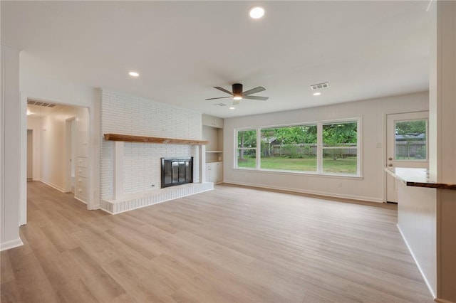 unfurnished living room featuring visible vents, ceiling fan, light wood-style floors, baseboards, and a fireplace