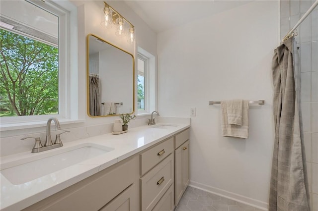 full bathroom featuring a healthy amount of sunlight, double vanity, and a sink
