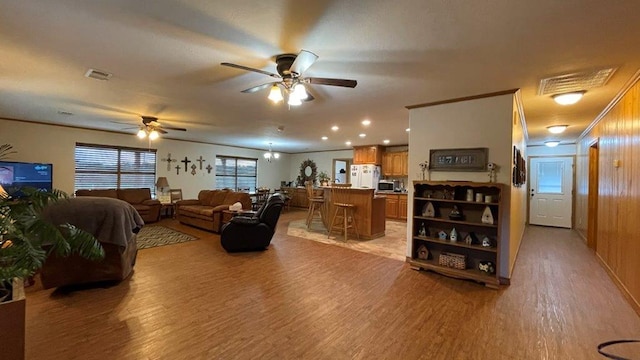 living room featuring light hardwood / wood-style flooring, ceiling fan, crown molding, and wood walls
