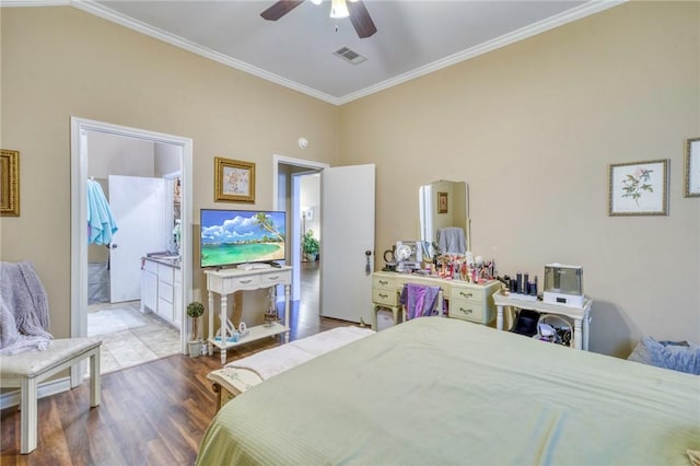 bedroom with visible vents, ornamental molding, wood finished floors, ensuite bath, and ceiling fan