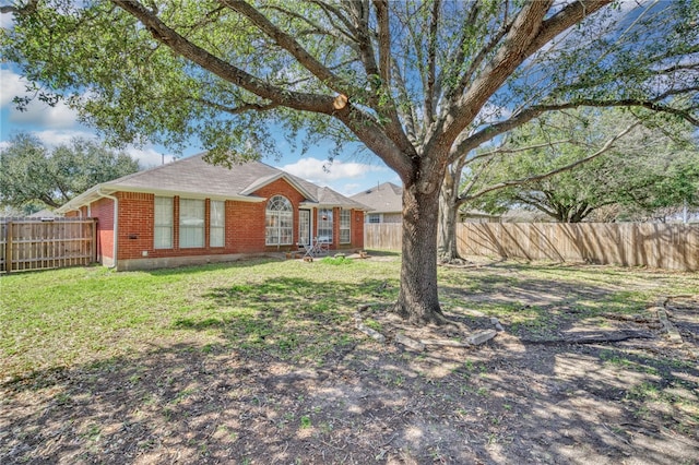 view of front facade with a front lawn, a fenced backyard, and brick siding