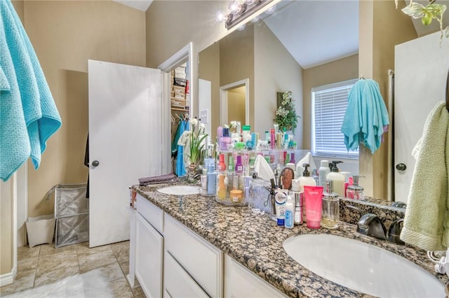 bathroom featuring double vanity, lofted ceiling, and a sink