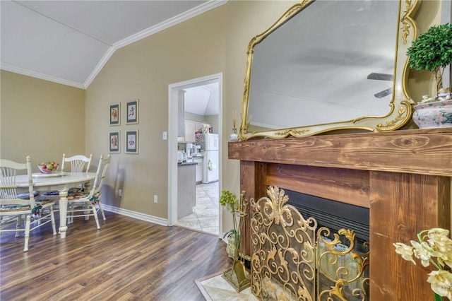 dining room featuring wood finished floors, crown molding, baseboards, and vaulted ceiling