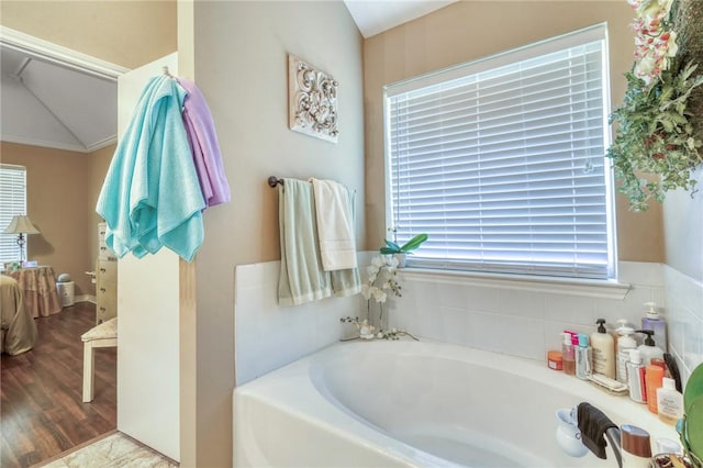 ensuite bathroom with a bath, wood finished floors, and ensuite bathroom