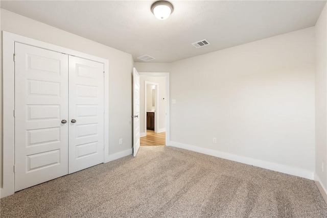 unfurnished bedroom featuring light colored carpet and a closet