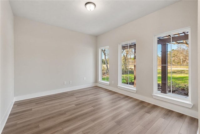 spare room featuring light hardwood / wood-style flooring and a healthy amount of sunlight