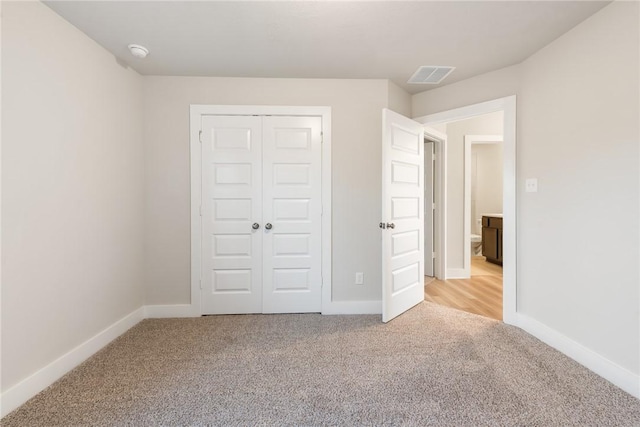 unfurnished bedroom with light carpet and a closet