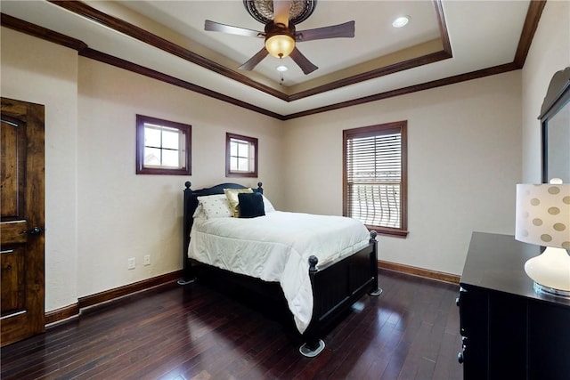 bedroom featuring baseboards, dark wood finished floors, ornamental molding, a raised ceiling, and a ceiling fan