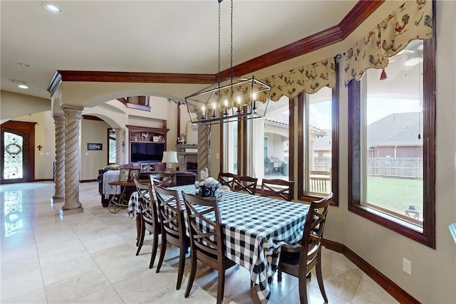 dining room with crown molding, baseboards, light tile patterned floors, arched walkways, and ornate columns