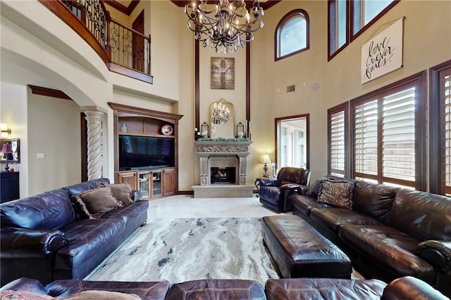 carpeted living room featuring visible vents, a large fireplace, arched walkways, a notable chandelier, and ornate columns