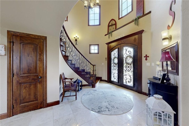 tiled foyer with stairs, a towering ceiling, french doors, and a wealth of natural light