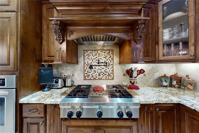 kitchen featuring tasteful backsplash, stainless steel appliances, and glass insert cabinets