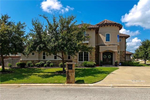 mediterranean / spanish-style house featuring stucco siding, stone siding, concrete driveway, and a front yard