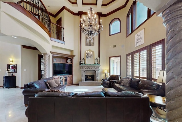 living area featuring decorative columns, arched walkways, crown molding, a notable chandelier, and a large fireplace