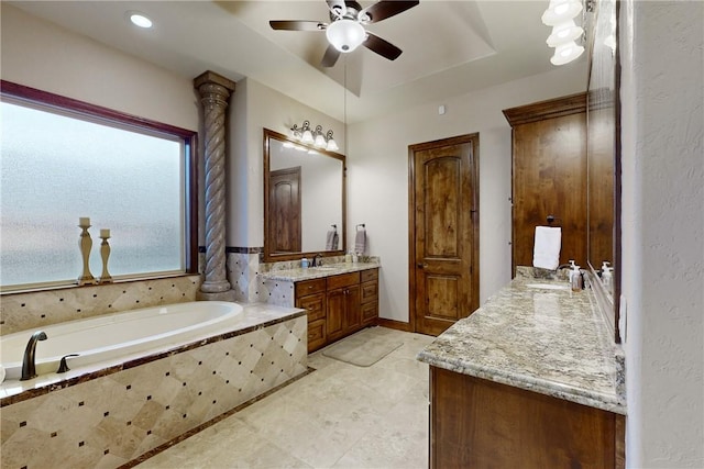 bathroom with a garden tub, two vanities, a ceiling fan, and a sink