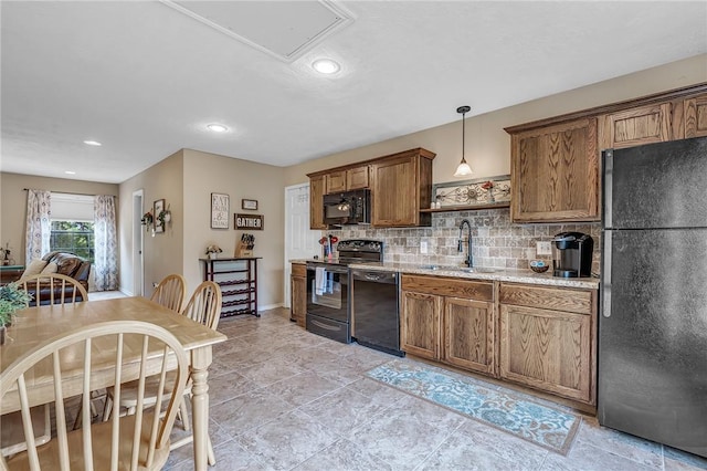 kitchen with sink, light stone counters, pendant lighting, black appliances, and tasteful backsplash