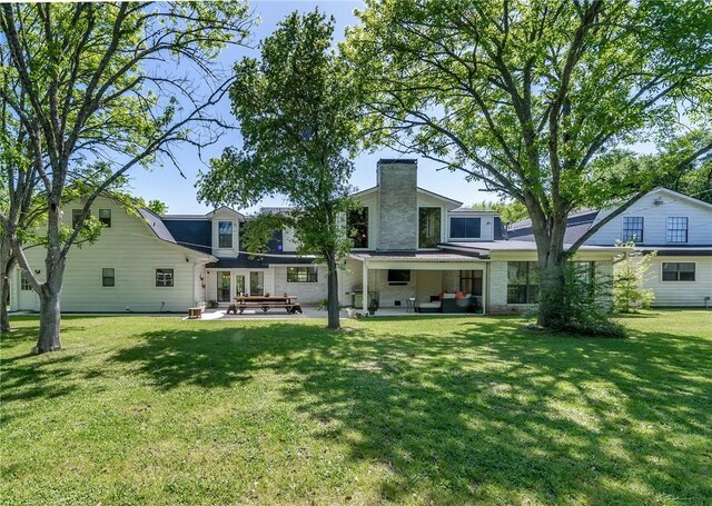 rear view of house with a patio and a lawn