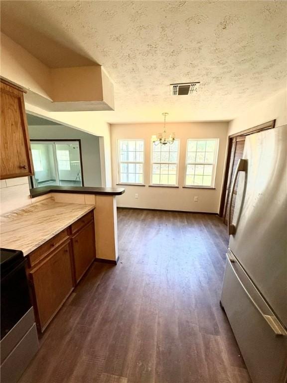 kitchen featuring dark wood-style flooring, a chandelier, visible vents, stainless steel electric stove, and freestanding refrigerator
