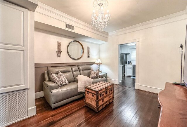 living room with dark hardwood / wood-style floors, ornamental molding, and a notable chandelier