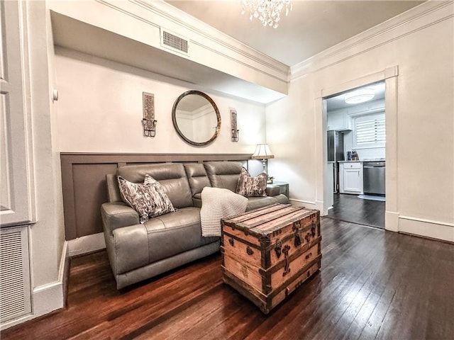 living room featuring dark hardwood / wood-style floors, ornamental molding, and an inviting chandelier