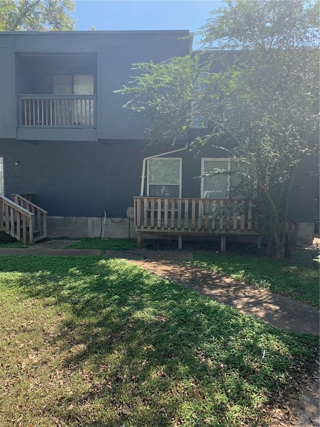 back of house featuring a lawn and a balcony