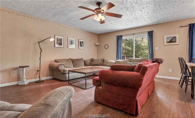 living room featuring wood-type flooring, a textured ceiling, and ceiling fan