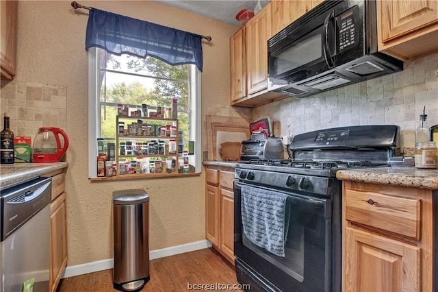 kitchen with light brown cabinets, tasteful backsplash, light hardwood / wood-style floors, and black appliances