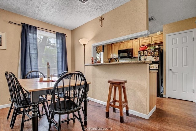 dining space featuring hardwood / wood-style flooring and a textured ceiling