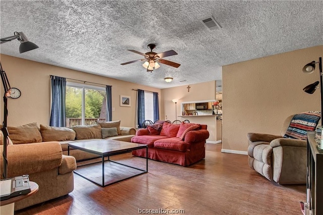 living room featuring ceiling fan, a textured ceiling, and hardwood / wood-style flooring