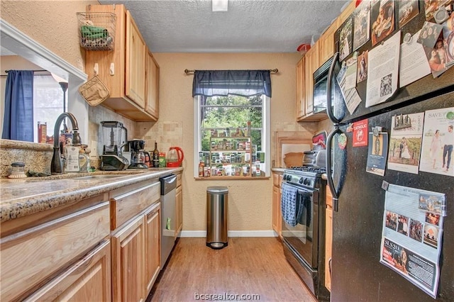 kitchen with sink, light hardwood / wood-style flooring, a textured ceiling, light brown cabinetry, and black appliances