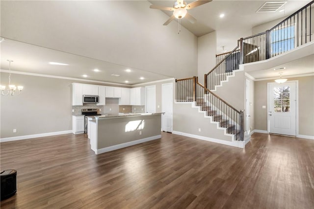 kitchen with appliances with stainless steel finishes, white cabinetry, decorative light fixtures, and a kitchen island