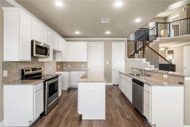 kitchen featuring white cabinets, stainless steel appliances, a kitchen island with sink, and sink