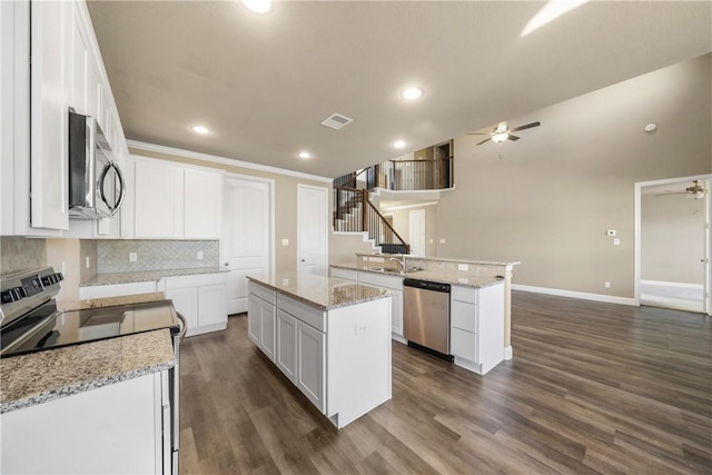 kitchen featuring stainless steel appliances, white cabinets, a center island, ceiling fan, and kitchen peninsula