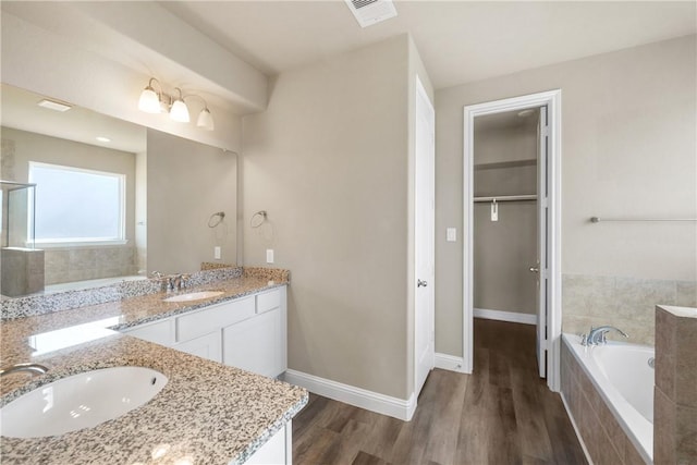 bathroom featuring vanity, hardwood / wood-style floors, and tiled bath