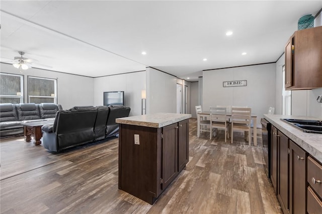 kitchen featuring dark brown cabinetry, dark wood finished floors, a ceiling fan, and light countertops