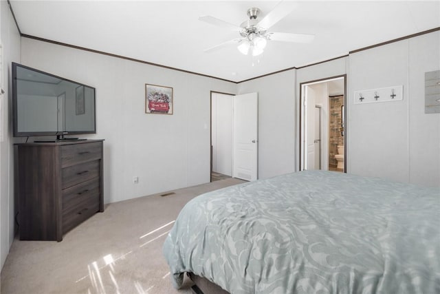 bedroom featuring carpet flooring, ensuite bath, crown molding, and a ceiling fan