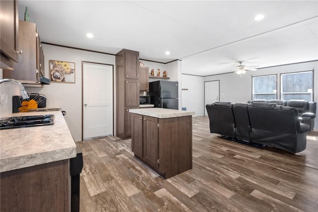 kitchen featuring a sink, black appliances, light countertops, dark brown cabinetry, and dark wood-type flooring