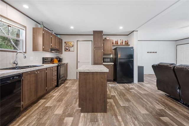 kitchen featuring black appliances, a center island, dark wood-style floors, and a sink